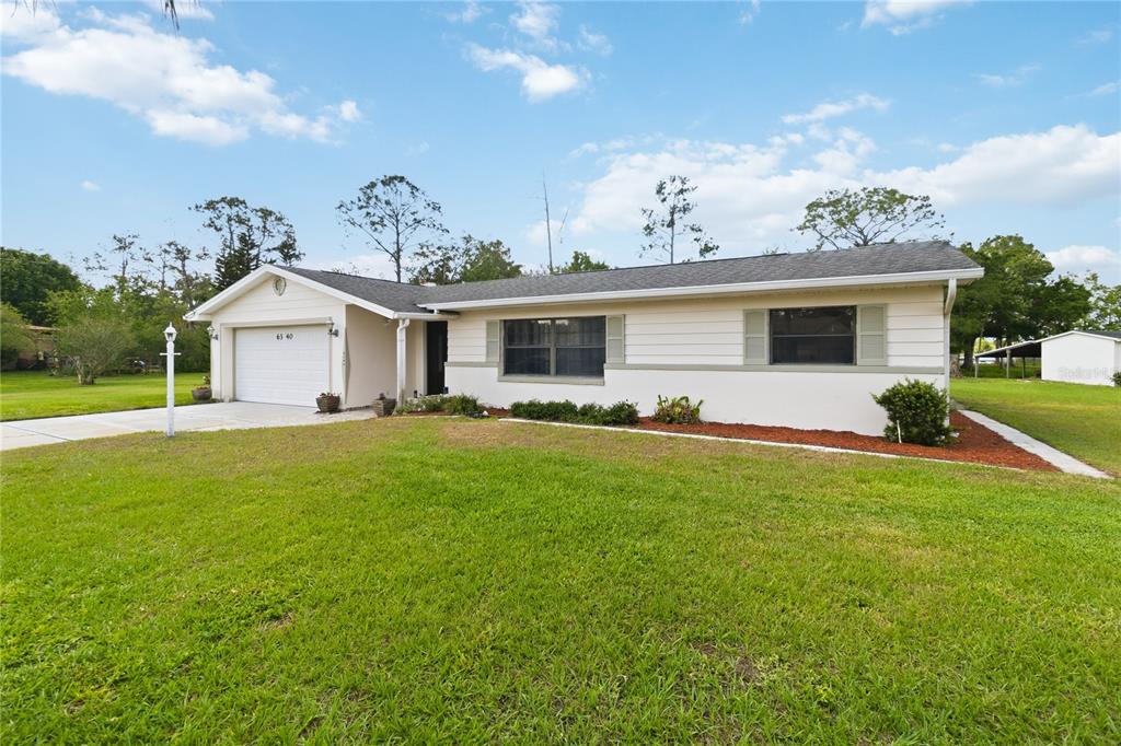 A single-story house with light-colored siding, a two-car garage, and a large front lawn — 6340 JUDITH COURT, ST CLOUD, FL
