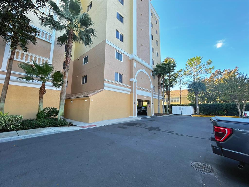 A multi-story building exterior with a parking entrance, palm trees, and a parked truck — 6336 BUFORD STREET UNIT 605, ORLANDO, FL