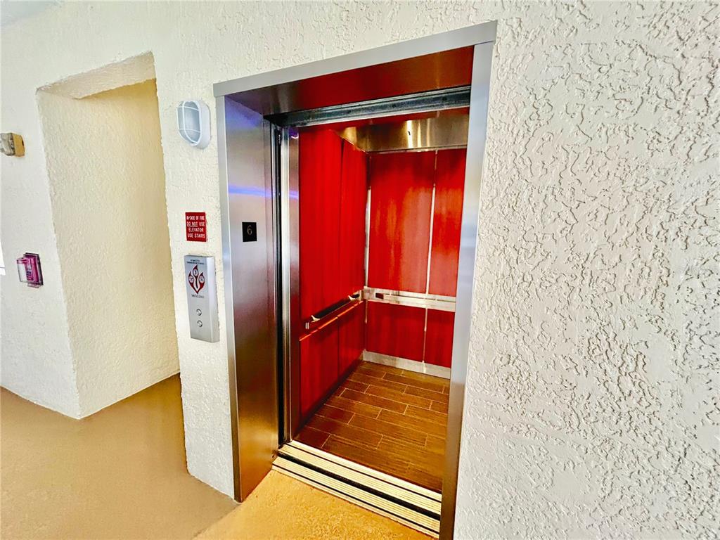 An elevator with red wood-paneled walls and a wood-look floor opens into a hallway — 6336 BUFORD STREET UNIT 605, ORLANDO, FL