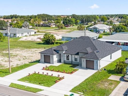 An aerial view shows a gray single-story house with a dark roof and a concrete driveway — 1315/1317 DIPLOMAT PARKWAY E, CAPE CORAL, FL