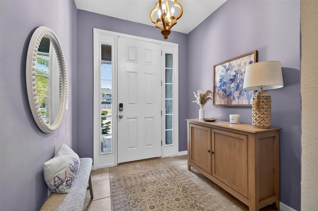 A foyer features lavender walls, a white front door, a wooden console table, and tile flooring — 6544 CALYPSO CORAL LANE, SARASOTA, FL