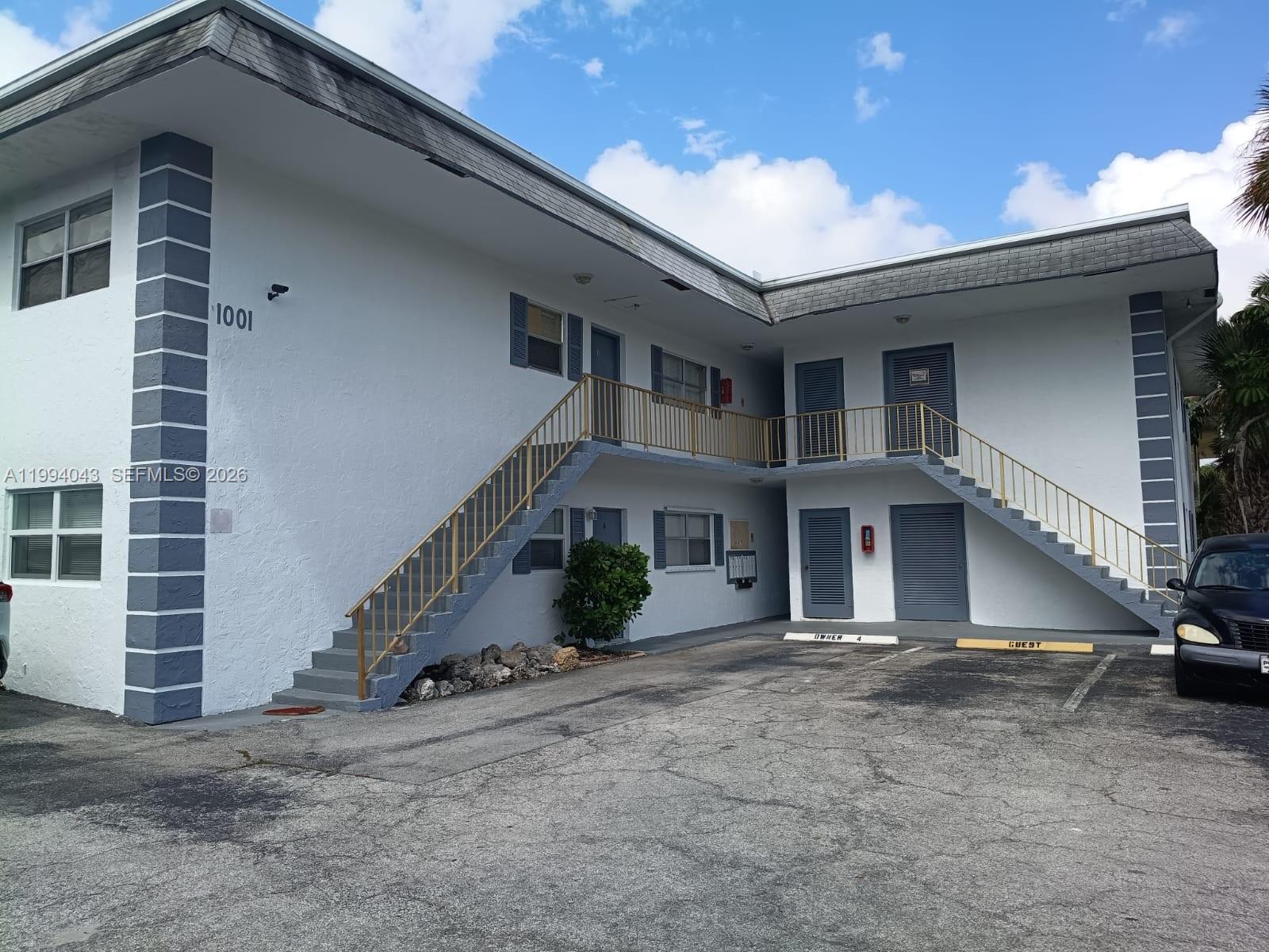 A two-story apartment building features white exterior walls, a metal staircase, and a parking lot — 1001 NW 45th St # 6, Deerfield Beach FL 33064, DEERFIELD BEACH, FL