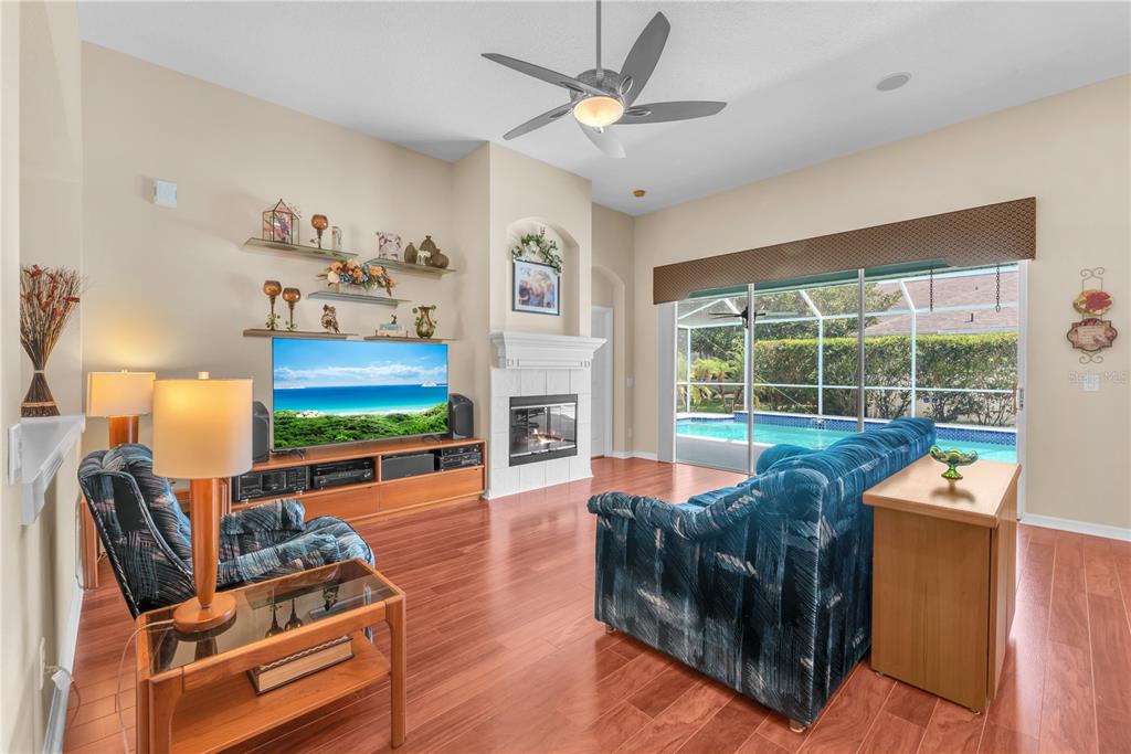 A living room with wood floors, a fireplace, and sliding doors overlooking a swimming pool — 2219 LONGMORE CIRCLE, VALRICO, FL