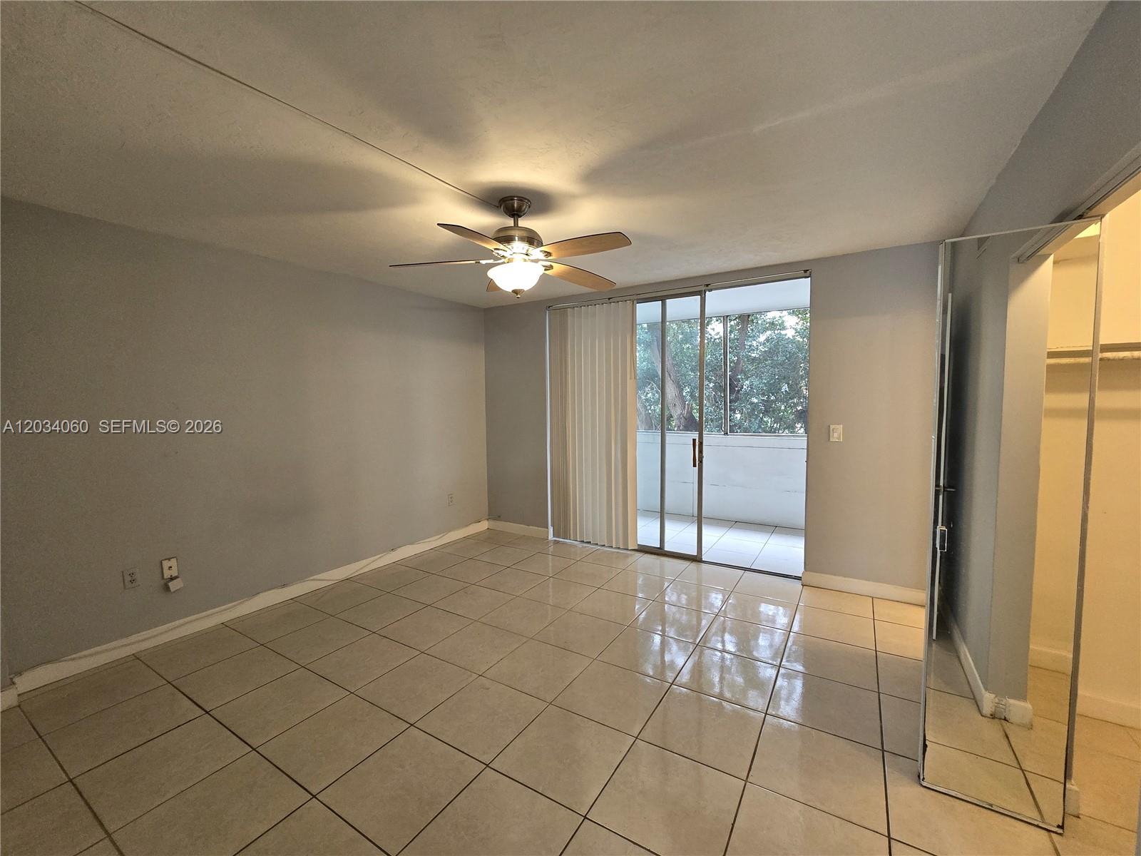 A bedroom features light gray walls, large floor tiles, a ceiling fan, and a balcony — 1475 NE 125th Ter # B, North Miami FL 33161, NORTH MIAMI, FL