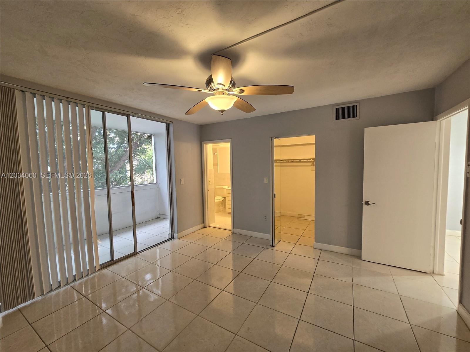 A bedroom features light tile flooring, a ceiling fan, a walk-in closet, and a balcony — 1475 NE 125th Ter # B, North Miami FL 33161, NORTH MIAMI, FL