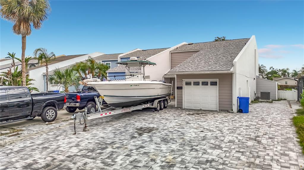 A boat on a trailer is parked in the driveway of a suburban house — 8725 BAY POINTE DRIVE, TAMPA, FL
