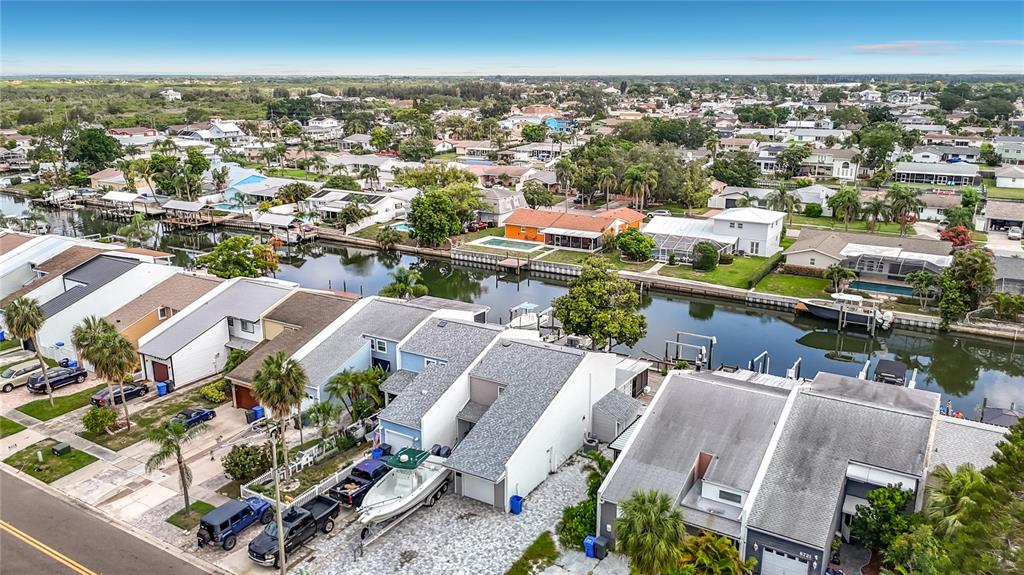 An aerial view shows waterfront townhomes with boat slips along a canal in a neighborhood — 8725 BAY POINTE DRIVE, TAMPA, FL