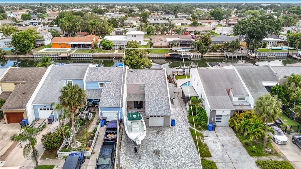 An aerial view shows a waterfront house with a boat parked in the paved driveway — 8725 BAY POINTE DRIVE, TAMPA, FL