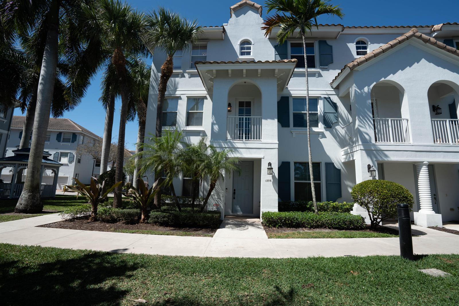 A three-story white stucco townhouse with a balcony, arched entryway, and palm trees in front — 1356 Piazza Pitti, Boynton Beach FL 33426, BOYNTON BEACH, FL