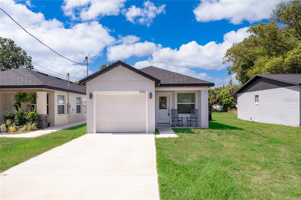 A single-story house with a white garage, gray roof, and a small front porch — 1946 HOLLYWOOD AVENUE, EUSTIS, FL