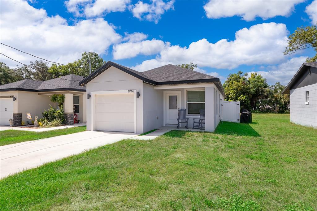 A single-story house with a white garage, gray exterior, and two rocking chairs on the porch — 1946 HOLLYWOOD AVENUE, EUSTIS, FL
