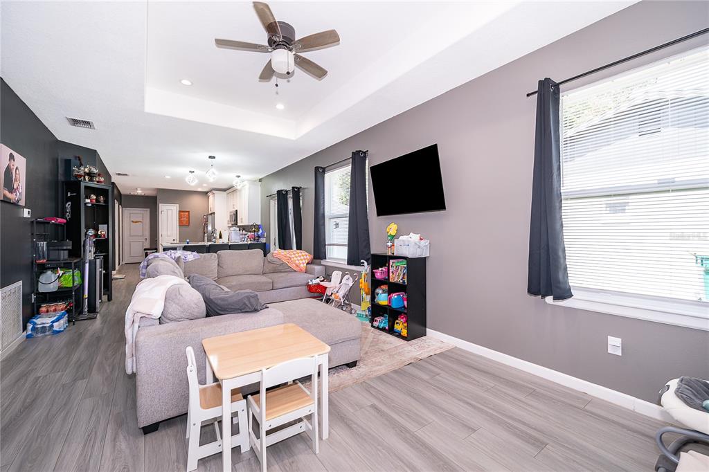 A living room with gray walls, wood-look flooring, a sectional sofa, and a ceiling fan — 1946 HOLLYWOOD AVENUE, EUSTIS, FL