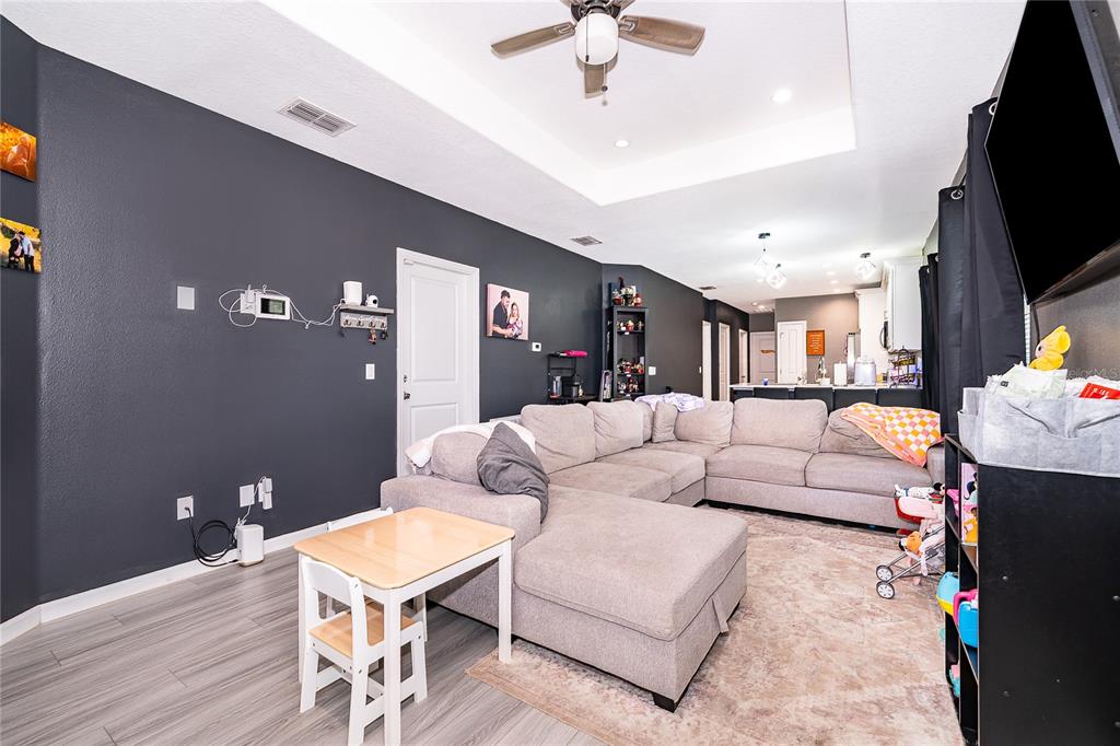 A living room features a large gray sectional sofa, a small table, and dark walls — 1946 HOLLYWOOD AVENUE, EUSTIS, FL
