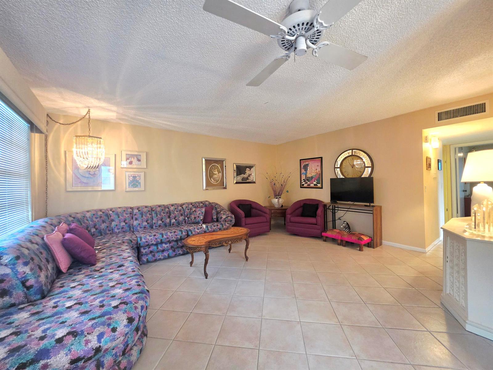 A living room features a large patterned sectional sofa, two purple armchairs, and tile flooring — 719 Flanders O, Delray Beach FL 33484, DELRAY BEACH, FL