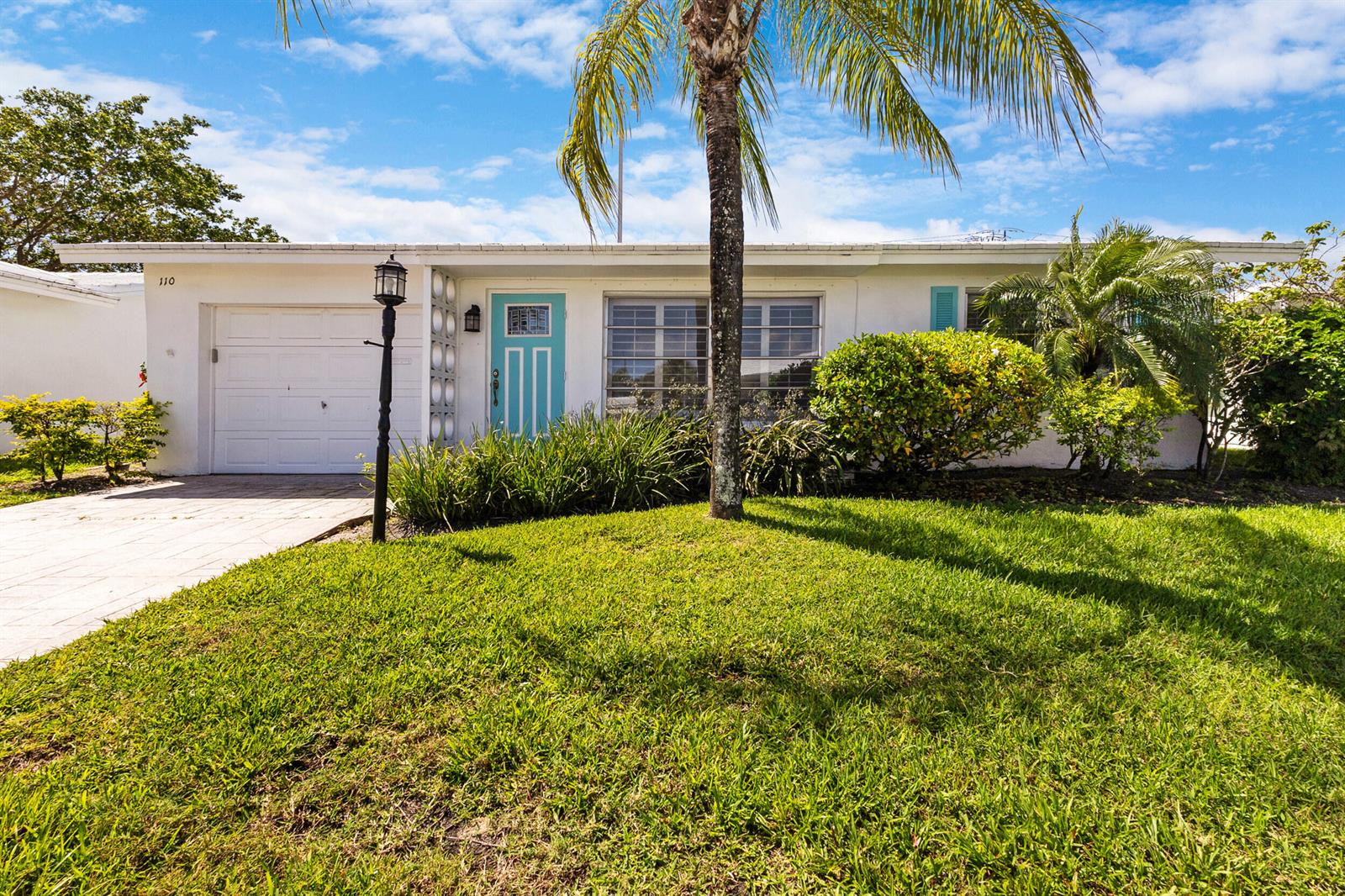 A single-story white house with a turquoise front door and a palm tree in front — 110 NW 24th Court, Pompano Beach FL 33064, POMPANO BEACH, FL