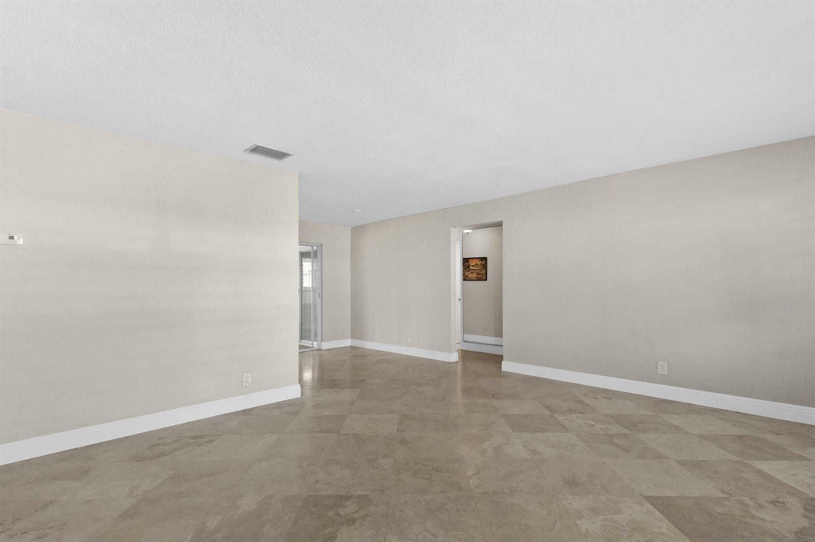 An empty room with beige walls, large square floor tiles, and a doorway leading elsewhere — 110 NW 24th Court, Pompano Beach FL 33064, POMPANO BEACH, FL