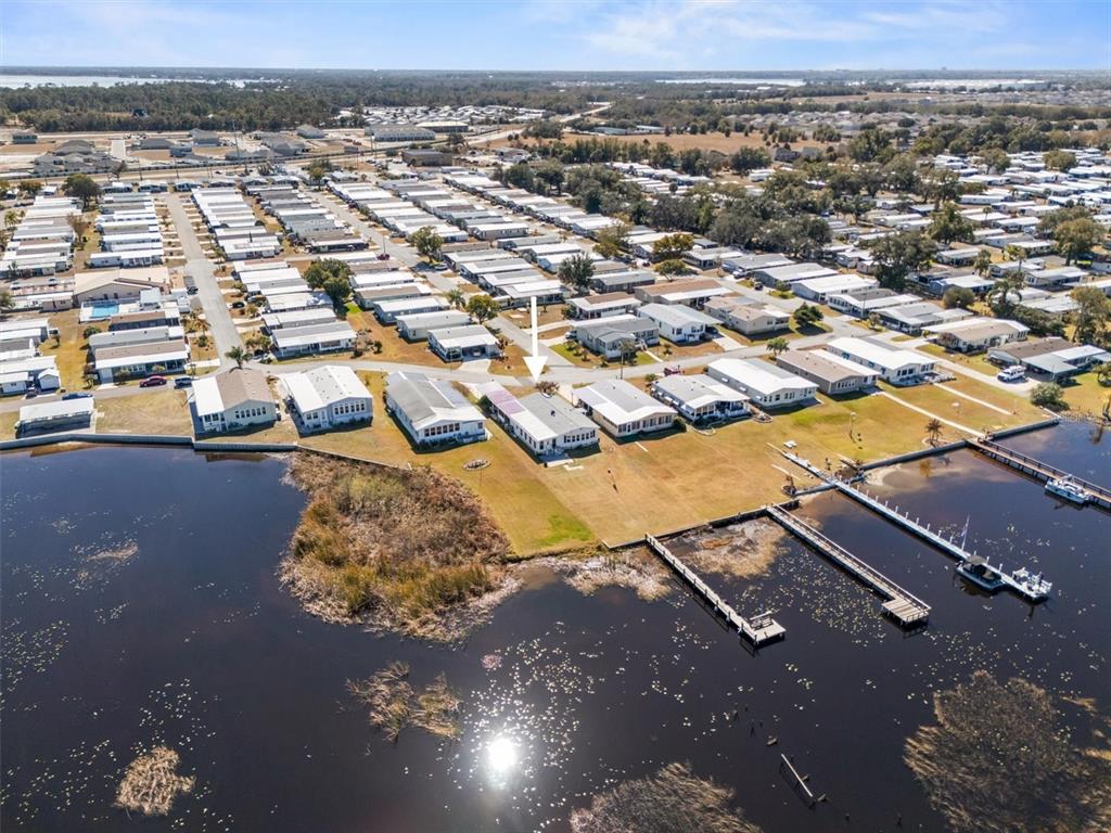 An aerial view shows a waterfront mobile home community with docks extending into the lake — 6825 S LAKE HENRY DRIVE NE, WINTER HAVEN, FL
