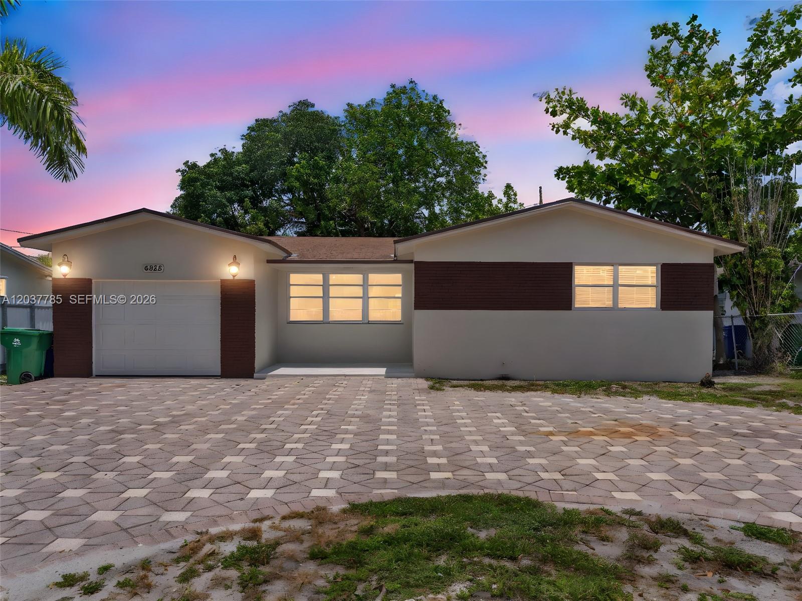 A single-story house with a paved driveway, white garage door, and brown brick accents — 6525 SW 18th St, Miramar FL 33023, MIRAMAR, FL