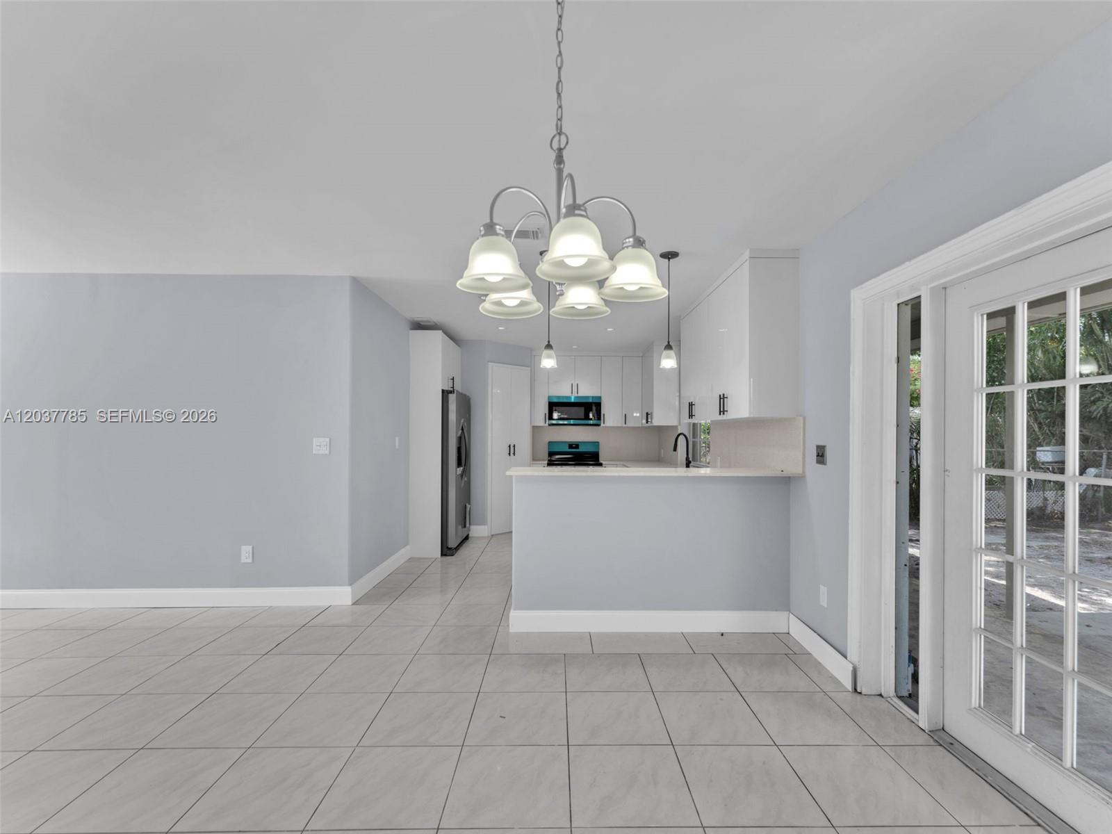A kitchen with white cabinets, a breakfast bar, and tile flooring opens to a dining area — 6525 SW 18th St, Miramar FL 33023, MIRAMAR, FL