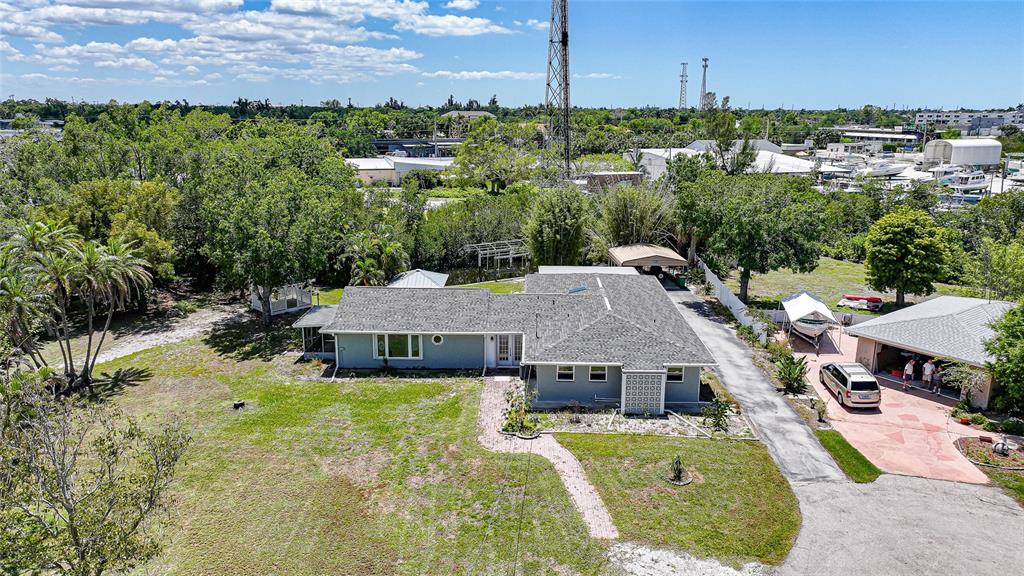 An aerial view shows a single-story house with a gray roof, driveway, and detached garage — 425 FIREBALL COURT, PUNTA GORDA, FL