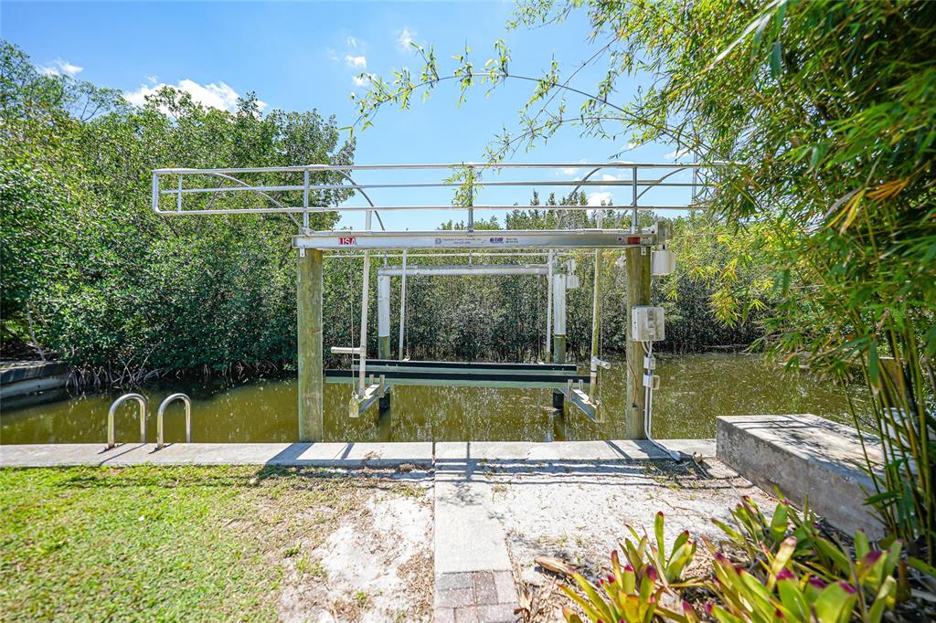 A boat lift stands over a canal surrounded by dense vegetation and trees — 425 FIREBALL COURT, PUNTA GORDA, FL