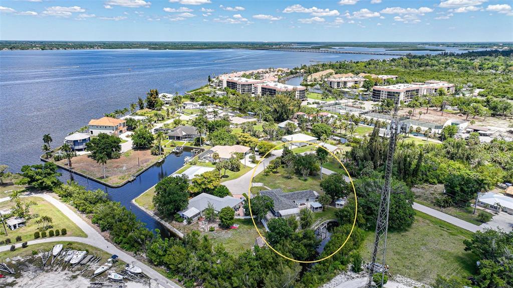 An aerial view shows a waterfront residential property circled in yellow near a communication tower — 425 FIREBALL COURT, PUNTA GORDA, FL