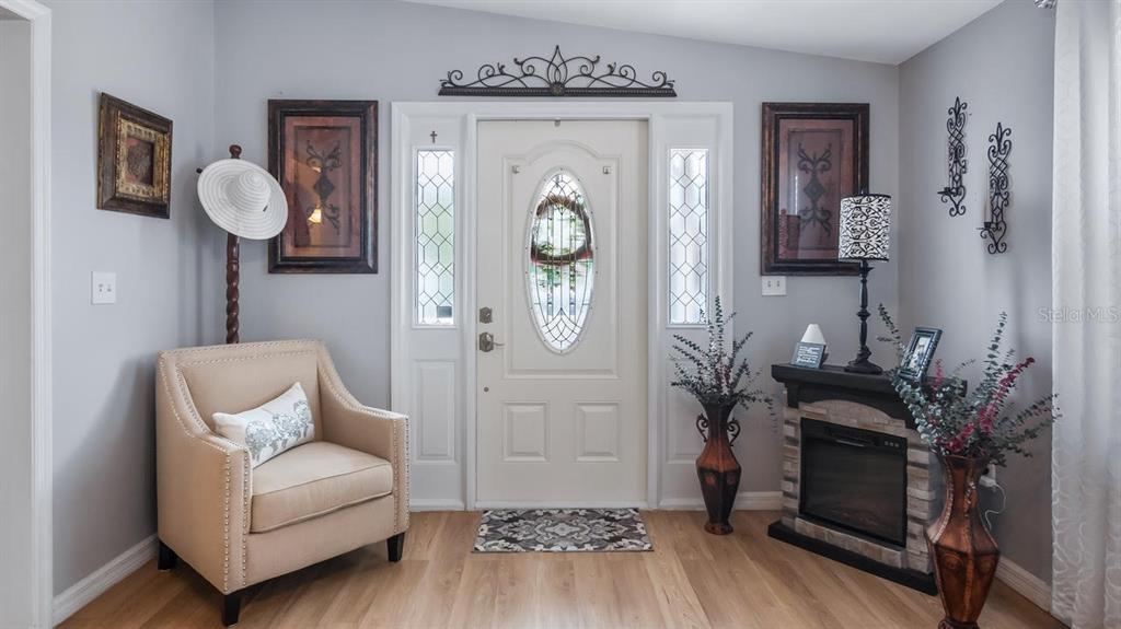 An entryway features a beige armchair, a white front door with glass, and a fireplace — 251 PATTERSON ROAD UNIT A27, HAINES CITY, FL