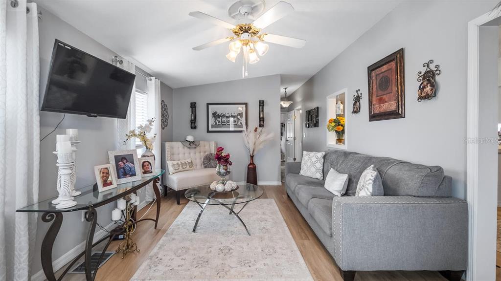 A living room features a gray sofa, glass coffee table, console table, and ceiling fan — 251 PATTERSON ROAD UNIT A27, HAINES CITY, FL