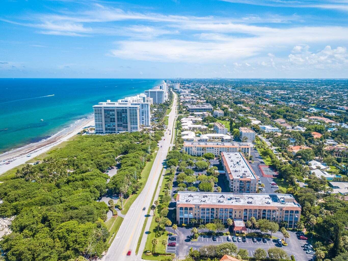 An aerial view shows a coastal road lined with apartment buildings, lush trees, and beach — 950 Ponce De Leon Road # 309, Boca Raton FL 33432, BOCA RATON, FL