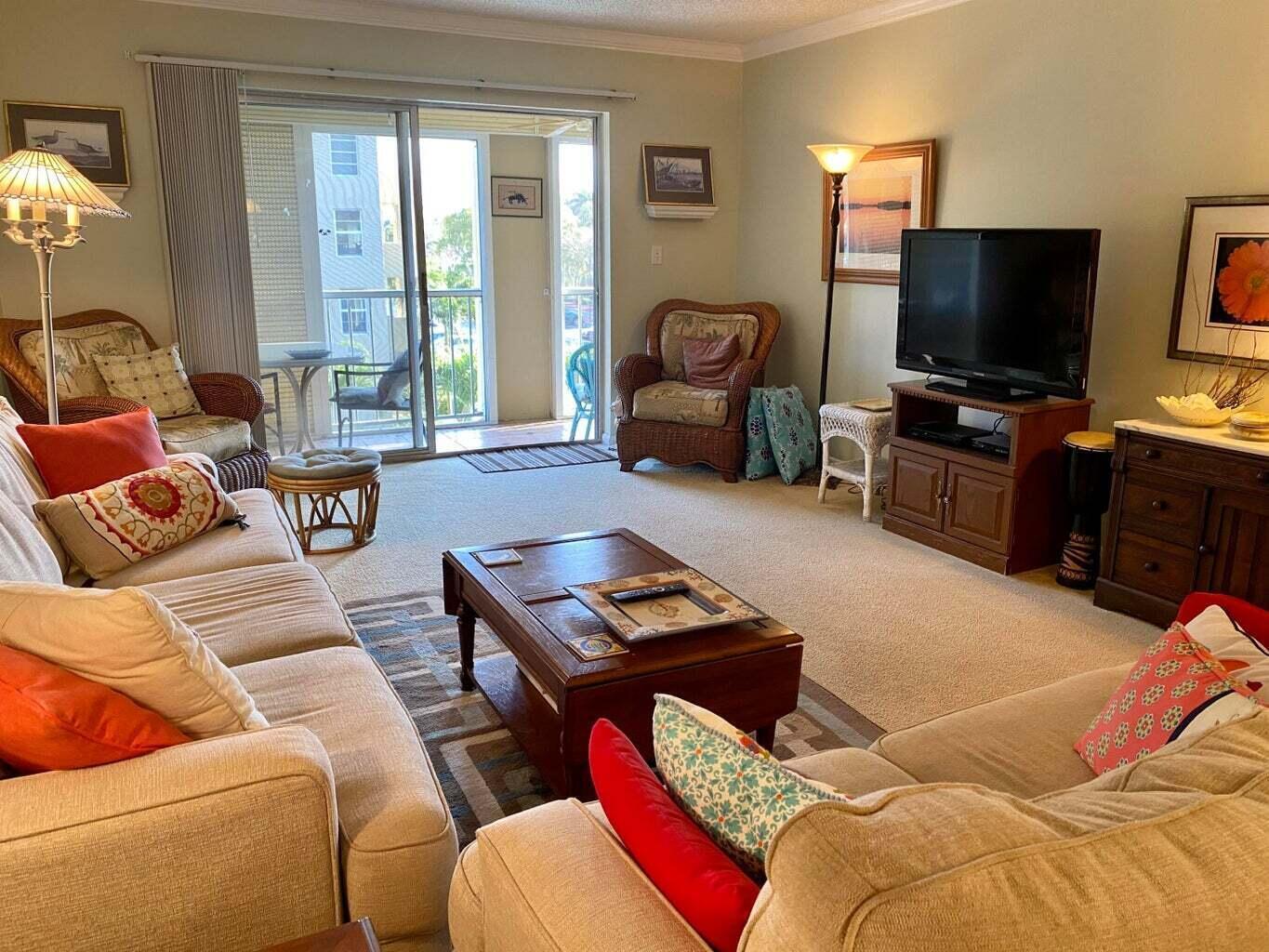 A living room with beige sofas, a wooden coffee table, and a sliding glass balcony door — 950 Ponce De Leon Road # 309, Boca Raton FL 33432, BOCA RATON, FL