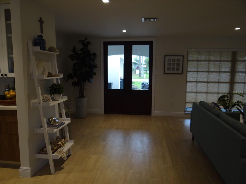 A living room features light wood-look tile flooring, a white ladder shelf, and double entry doors — 470 BAL HARBOR BOULEVARD, PUNTA GORDA, FL