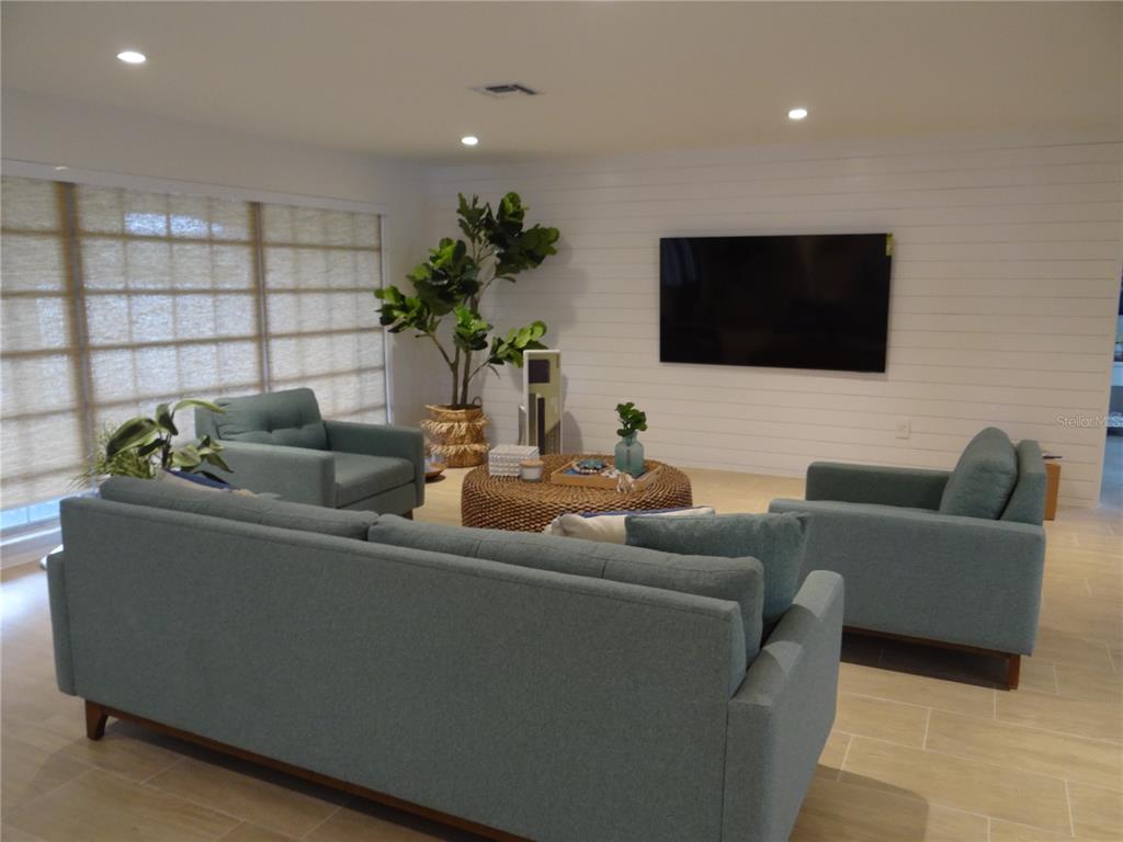 A living room features blue furniture, a round woven coffee table, and a shiplap wall — 470 BAL HARBOR BOULEVARD, PUNTA GORDA, FL