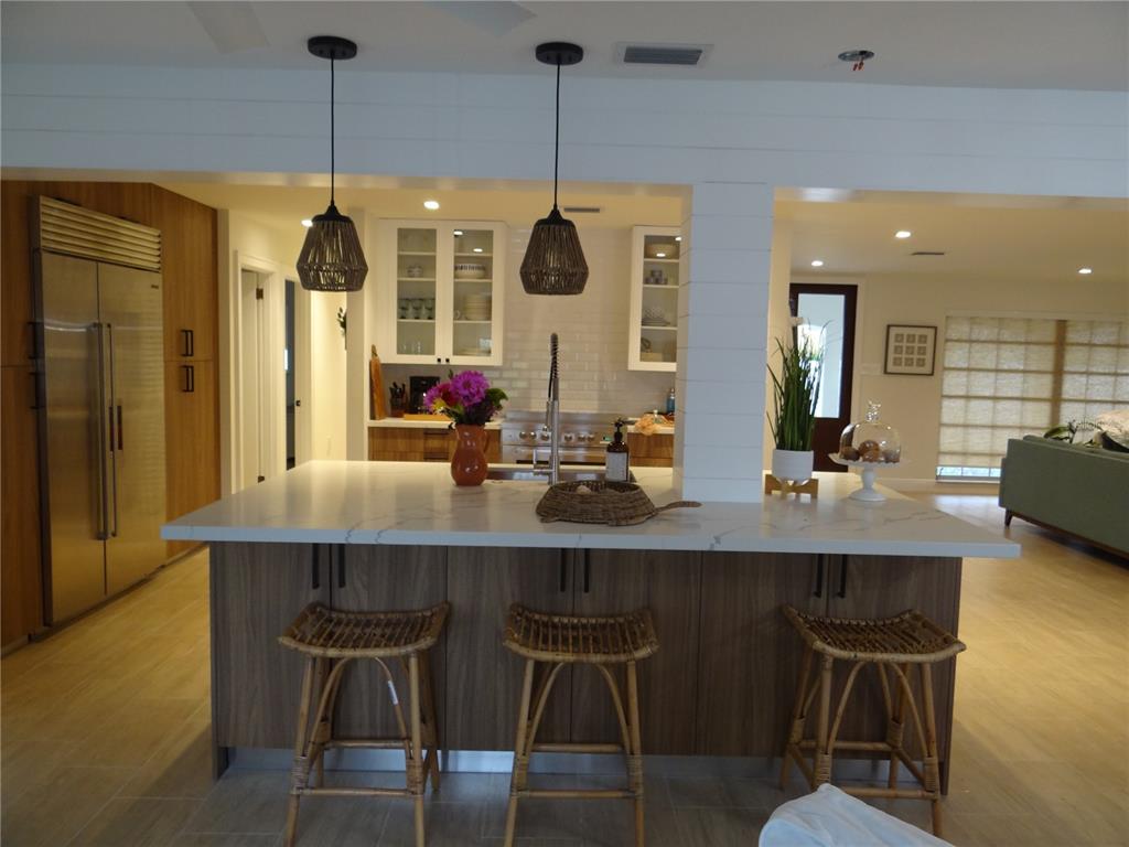 A kitchen features a large island with bar stools, wood cabinetry, and white countertops — 470 BAL HARBOR BOULEVARD, PUNTA GORDA, FL