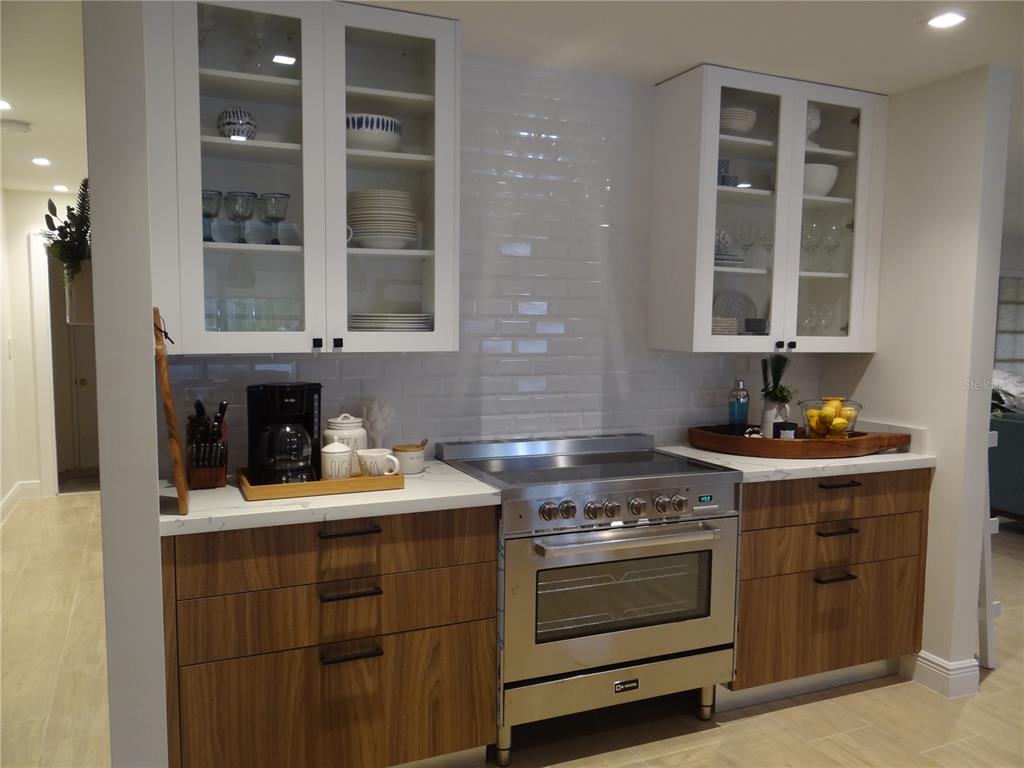 A kitchen features white upper cabinets, wood-toned lower cabinets, a stainless steel range, and subway tile — 470 BAL HARBOR BOULEVARD, PUNTA GORDA, FL
