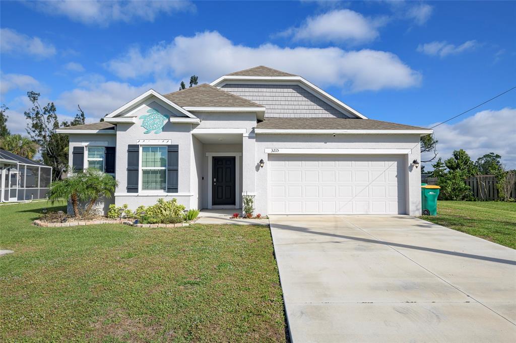 A single-story house with a white stucco exterior, a two-car garage, and a turtle decoration — 3215 BROOKLYN AVENUE, PORT CHARLOTTE, FL