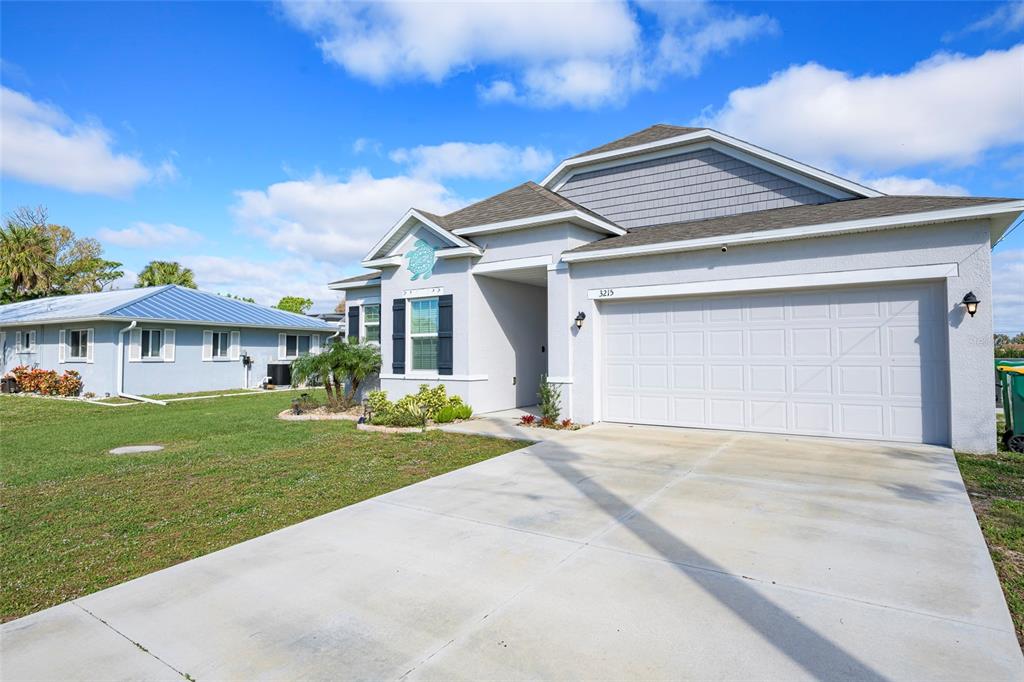 A single-story house with a two-car garage, gray stucco exterior, and a concrete driveway — 3215 BROOKLYN AVENUE, PORT CHARLOTTE, FL