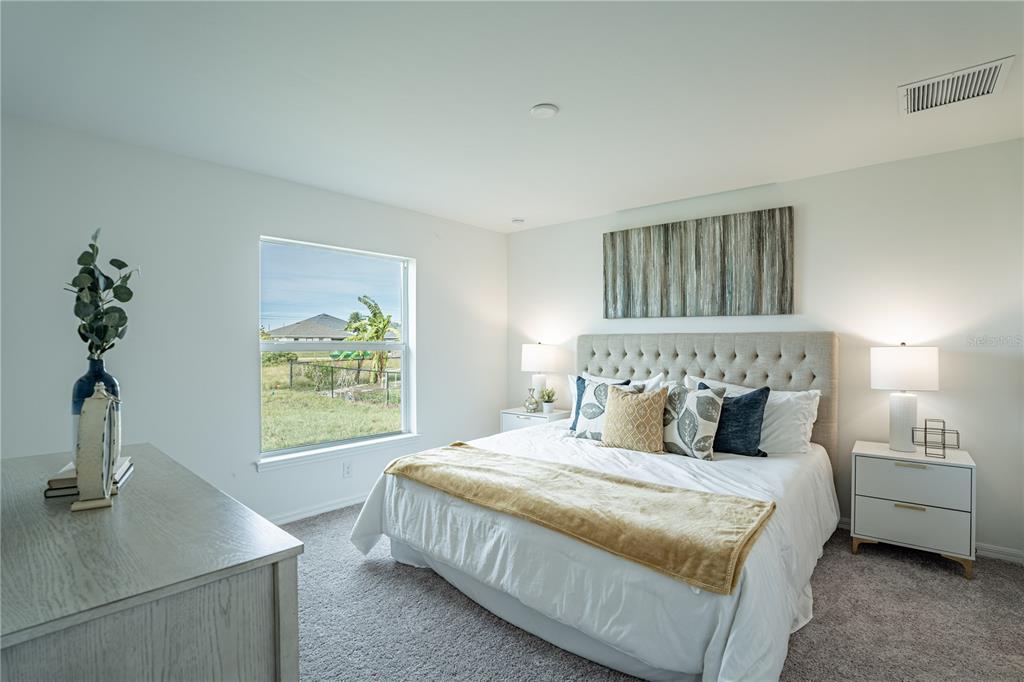 A bedroom features a tufted headboard, white bedding, two nightstands, and a window overlooking a field — 4319 HOGRATH STREET, PORT CHARLOTTE, FL