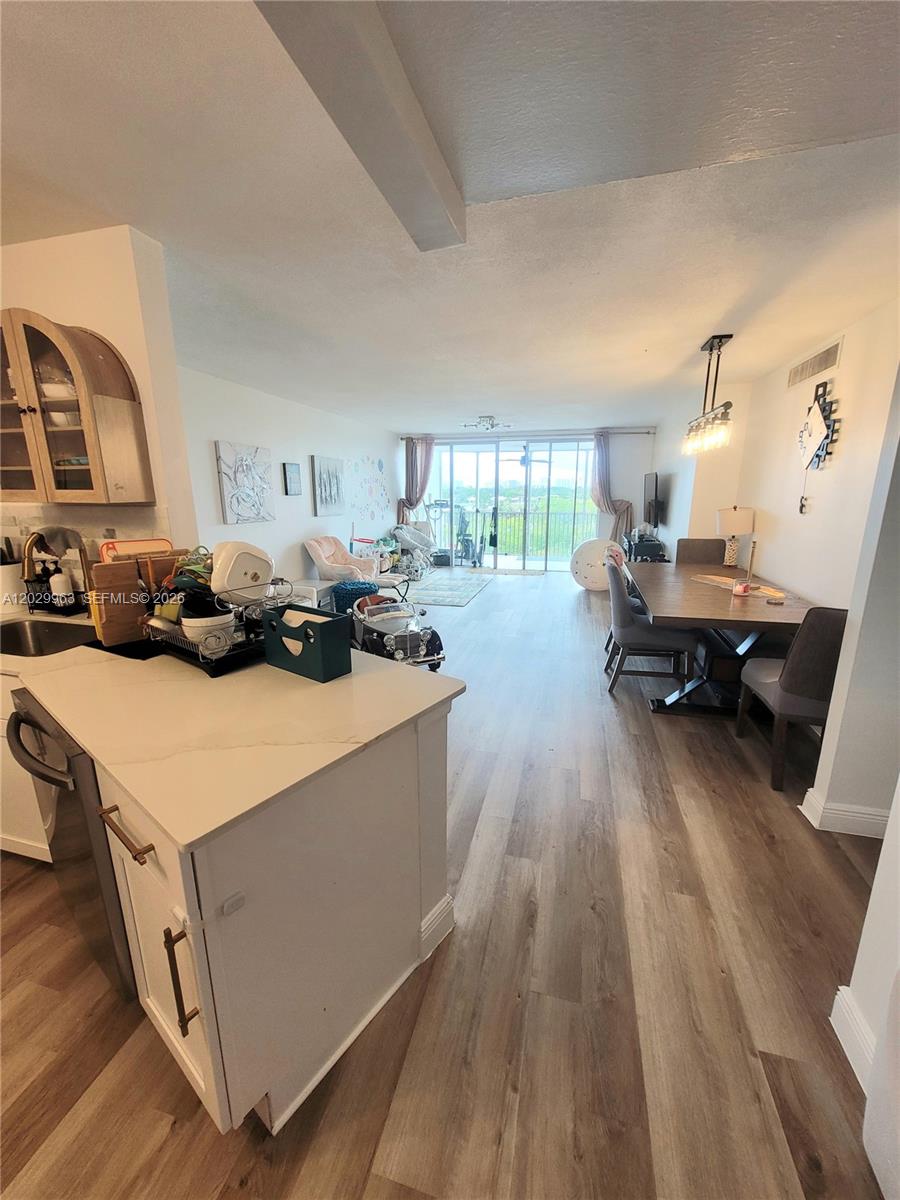 An open-concept living and dining area features wood-look flooring and a kitchen island — 1780 NE 191st St # 2, Miami FL 33179, MIAMI, FL