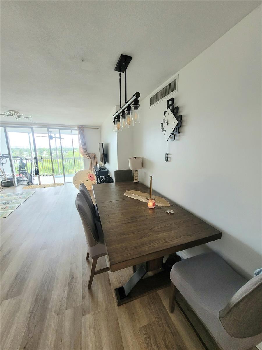A dining area features a wooden table, grey chairs, a pendant light, and a balcony view — 1780 NE 191st St # 2, Miami FL 33179, MIAMI, FL