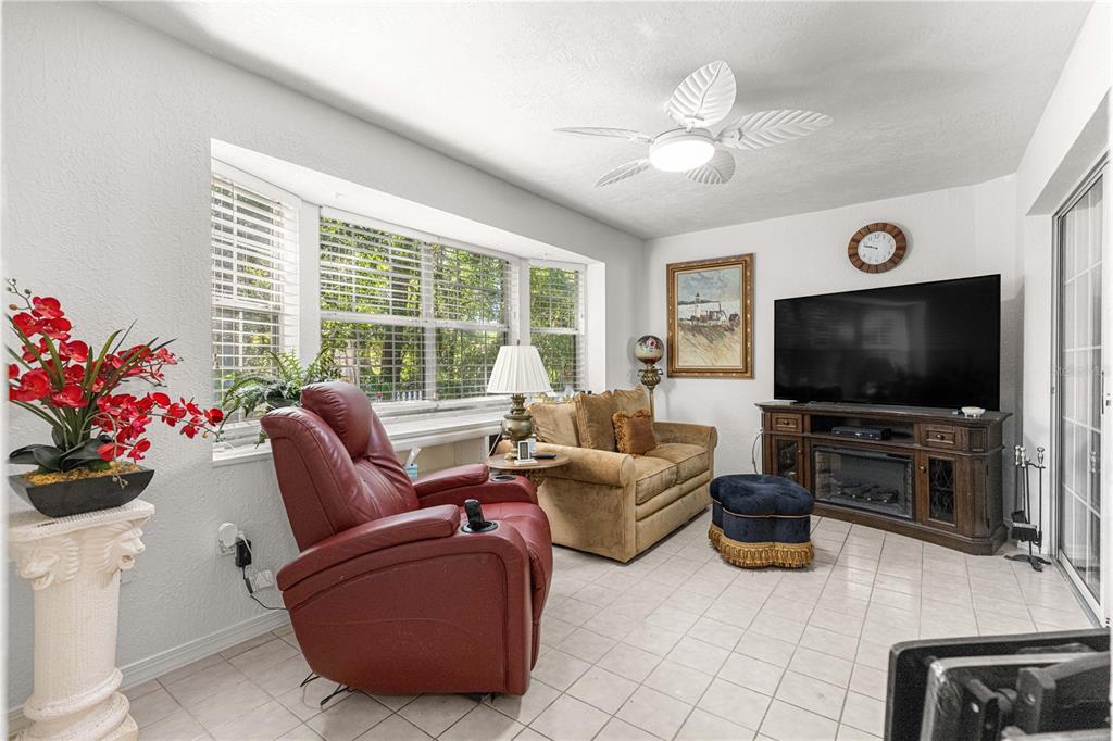A sunroom features a red recliner, a tan sofa, a television console, and tile flooring — 11465 SW 75TH TERRACE ROAD, OCALA, FL