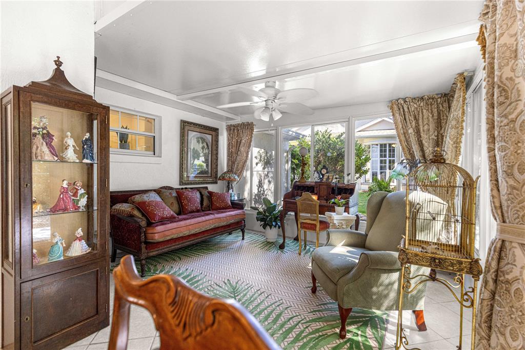 A sunroom features a patterned rug, a sofa, an armchair, and a wooden display cabinet — 11465 SW 75TH TERRACE ROAD, OCALA, FL