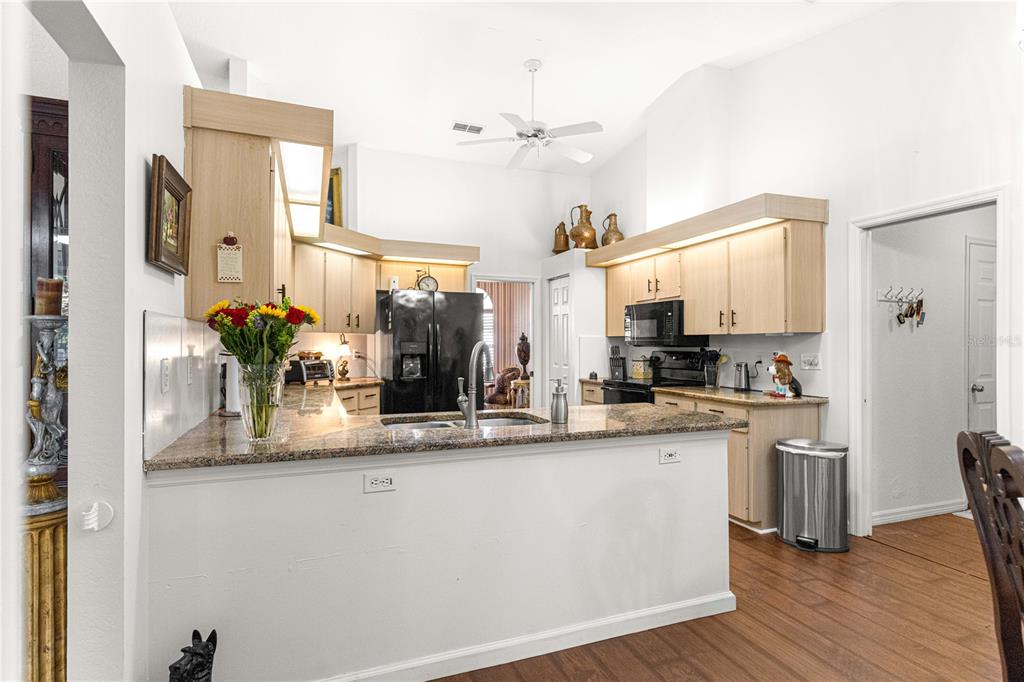 A kitchen features light wood cabinets, granite countertops, a breakfast bar, and stainless steel appliances — 11465 SW 75TH TERRACE ROAD, OCALA, FL