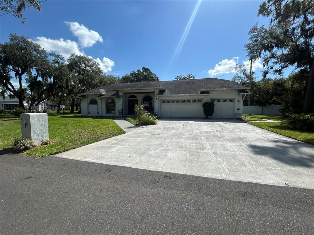A single-story house with a large concrete driveway, a three-car garage, and mature trees — 5235 POST LANE, LAKELAND, FL