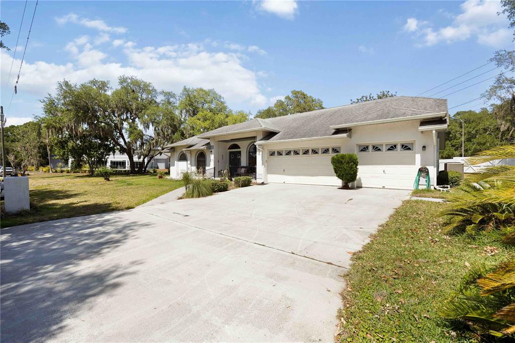 A single-story house with a white exterior, a three-car garage, and a concrete driveway — 5235 POST LANE, LAKELAND, FL