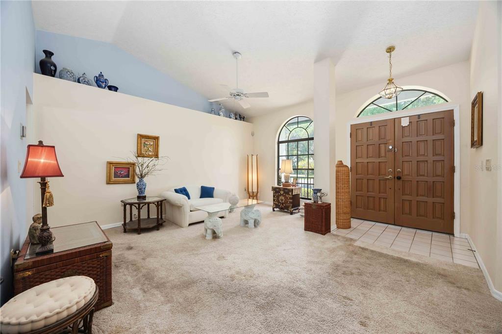 A living room with beige carpet, a vaulted ceiling, and a double-door entryway — 5235 POST LANE, LAKELAND, FL