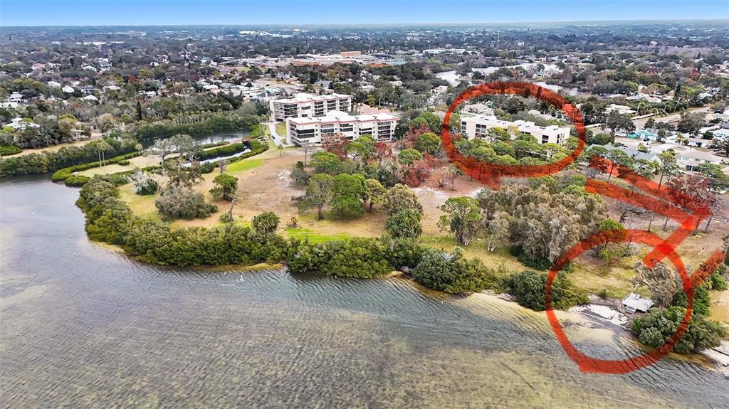 An aerial view shows a waterfront property with apartment buildings and a small wooden dock — 303 TARPON POINT, TARPON SPRINGS, FL