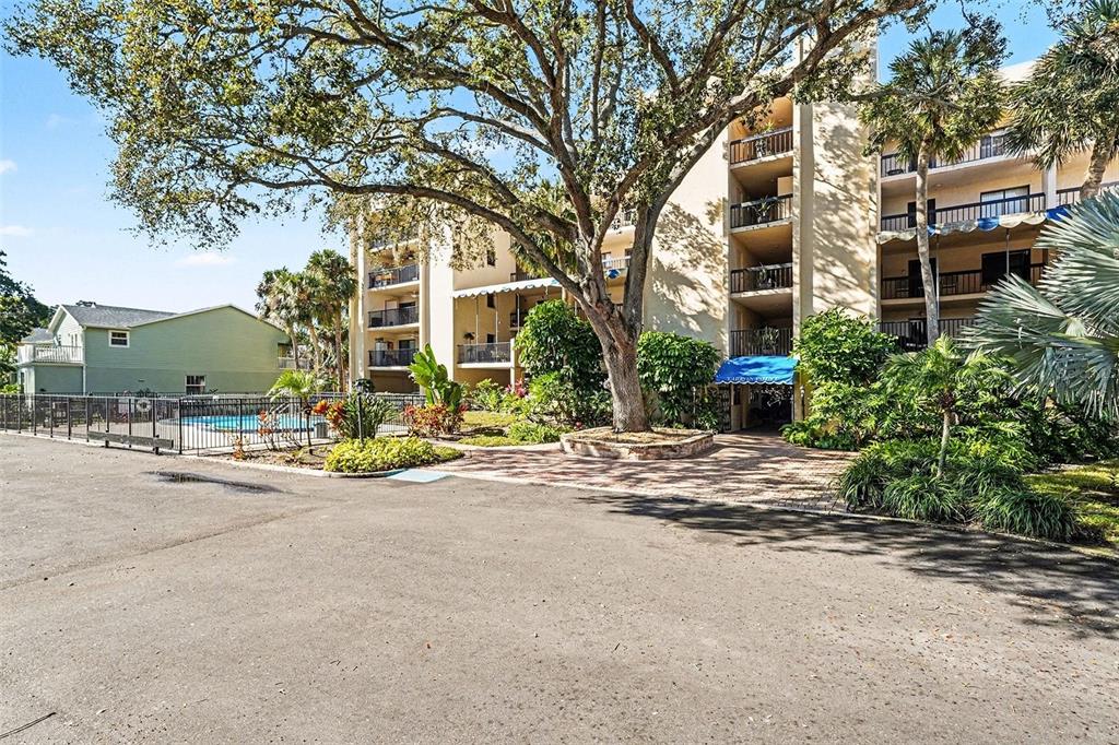A multi-story apartment building with balconies and a swimming pool behind a black fence — 303 TARPON POINT, TARPON SPRINGS, FL