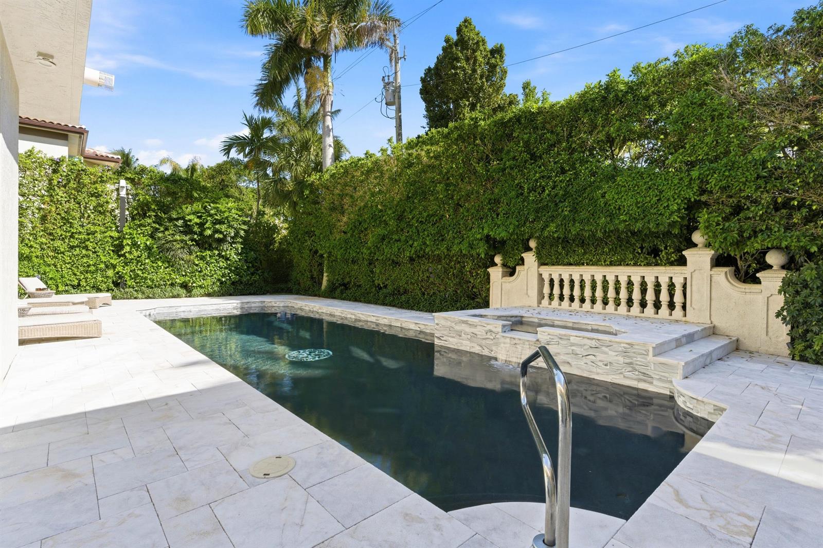 A rectangular swimming pool with a raised spa and stone patio sits in a backyard — 254 Atlantic Avenue, Palm Beach FL 33480, PALM BEACH, FL