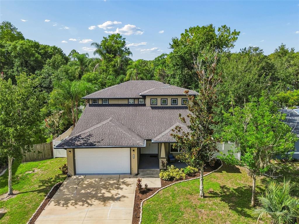 An aerial view of a two-story suburban house with a garage and surrounding trees — 21620 TEAL COURT, LUTZ, FL