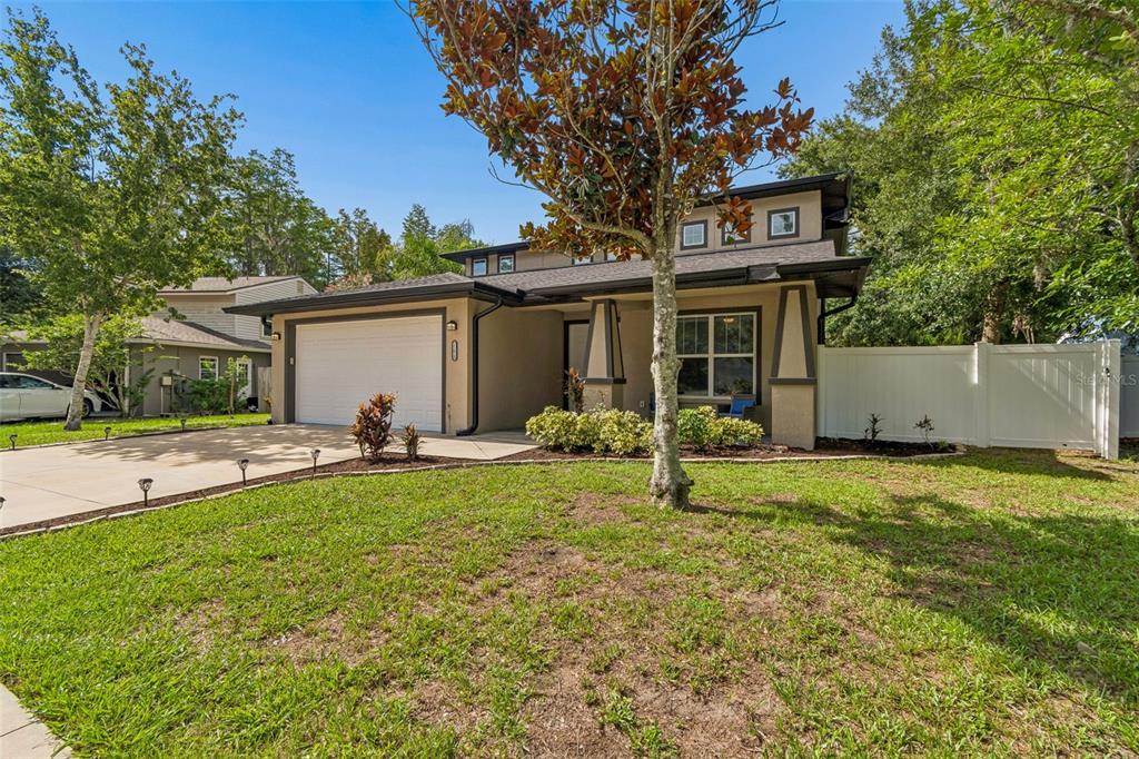 A two-story house with a tan exterior, a white garage door, and a white privacy fence — 21620 TEAL COURT, LUTZ, FL